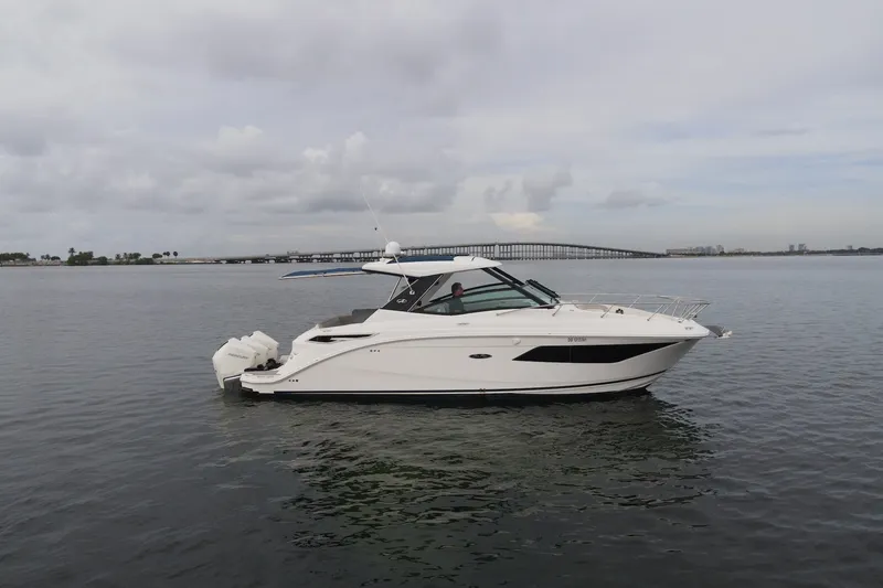 Slide: The Image of 2020 Sea Ray Sundancer 320 Coupe Outboard cruising on calm waters near a bridge. - 2