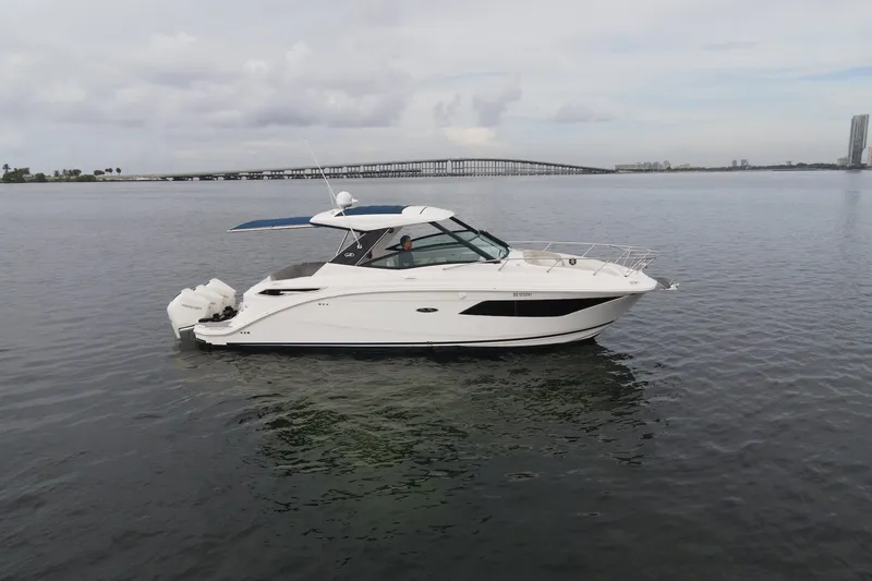 Slide: The Image of 2020 Sea Ray Sundancer 320 Coupe Outboard cruising on calm waters near a bridge. - 4