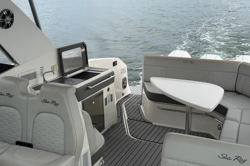 Slide: The Image of 2020 Sea Ray Sundancer 320 Coupe Outboard interior with seating and kitchenette on water. - 26