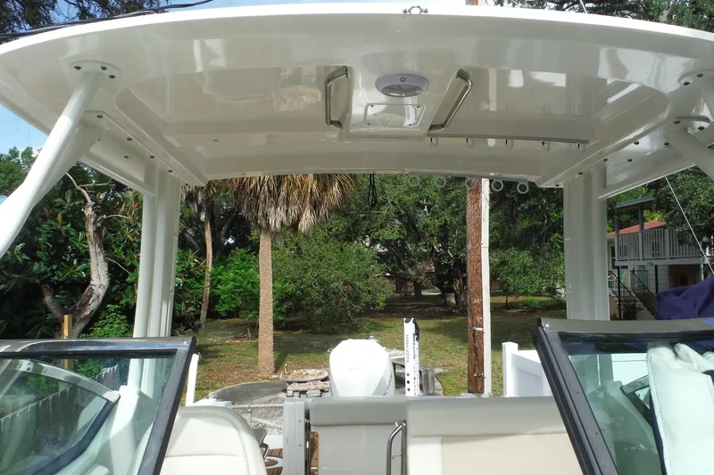 Slide: The Image of 2021 Boston Whaler 240 Vantage boat interior with canopy and seating, surrounded by lush greenery. - 34