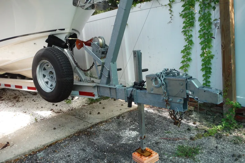 Slide: The Image of Trailer hitch and wheel of a 2021 Boston Whaler 240 Vantage boat, parked on gravel. - 53