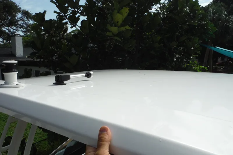 Slide: The Image of 2021 Boston Whaler 240 Vantage boat roof with hand and greenery background. - 37