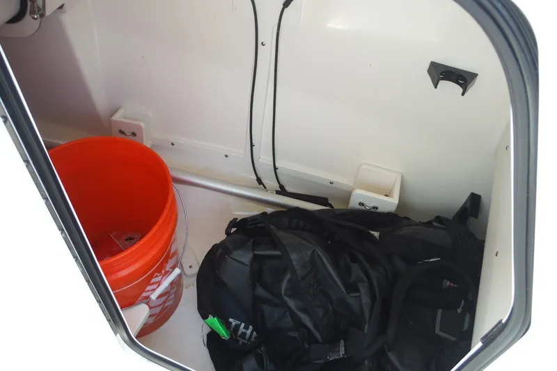 Slide: The Image of Storage compartment of 2021 Boston Whaler 240 Vantage with orange bucket and black bag. - 40