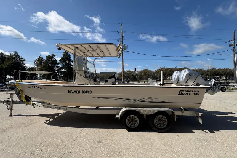 Slide: The Image of 2019 Carolina Skiff 24 DLX boat on trailer under clear blue sky. - 7