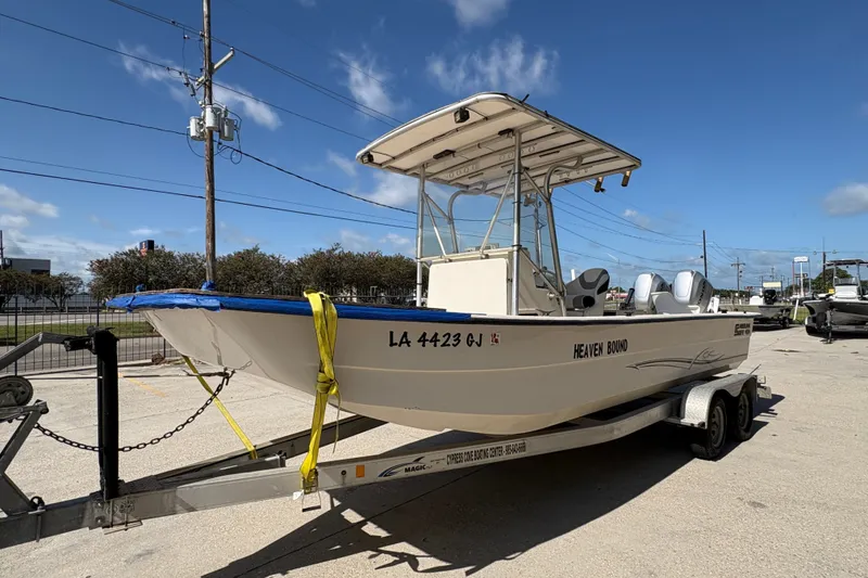 Slide: The Image of 2019 Carolina Skiff 24 DLX boat on trailer, parked outdoors under clear blue sky. - 8