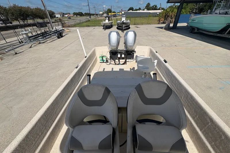 Slide: The Image of 2019 Carolina Skiff 24 DLX boat with dual engines and seating, parked outdoors. - 13