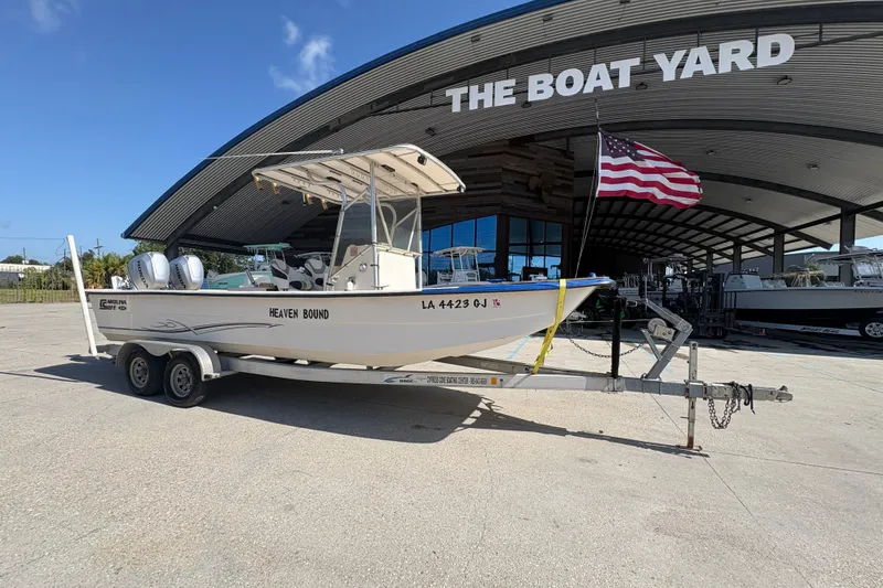 Slide: The Image of 2019 Carolina Skiff 24 DLX boat on trailer at The Boat Yard, American flag waving. - 2