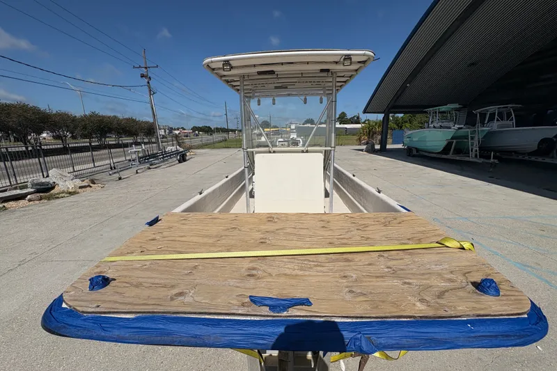 Slide: The Image of 2019 Carolina Skiff 24 DLX boat with wooden deck, parked outdoors under clear sky. - 11