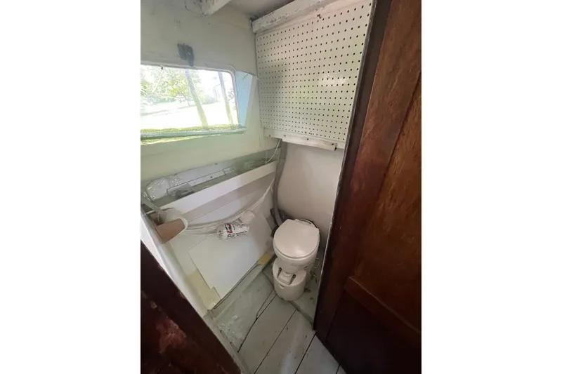 Slide: The Image of Small bathroom inside a 1970 Dyer 29 boat, featuring a toilet and window. - 18