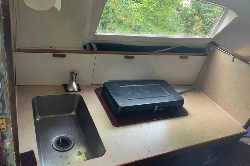 Slide: The Image of 1970 Dyer 29 boat interior with sink and portable stove in compact kitchen area. - 15