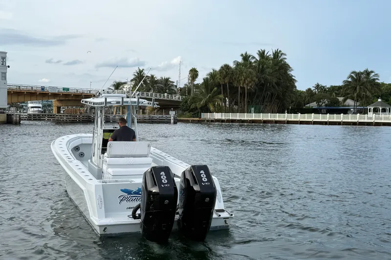Slide: The Image of 2011 Contender 35 ST boat cruising near a bridge with palm trees in the background. - 2