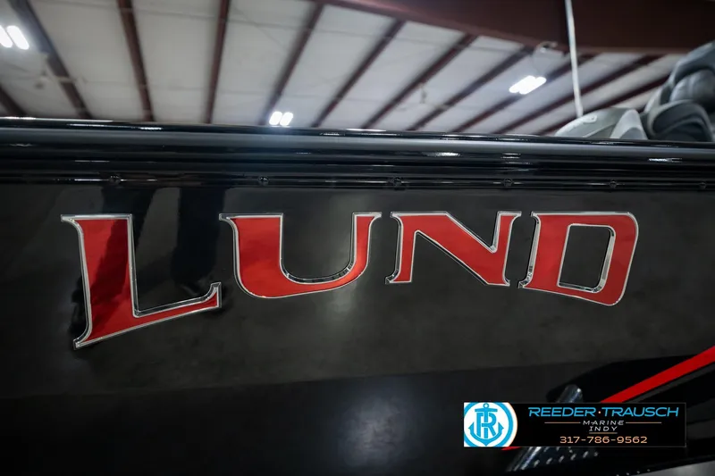 Slide: The Image of 2026 Lund 1875 Renegade boat with bold red logo in showroom setting. - 59