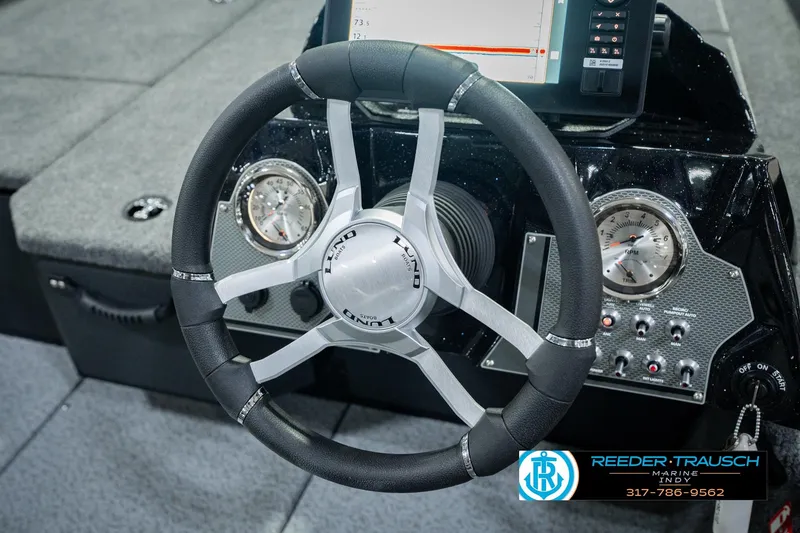 Slide: The Image of Steering wheel and dashboard of 2026 Lund 1875 Renegade boat, featuring modern controls. - 34