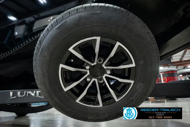 Slide: The Image of Close-up of a 2026 Lund 1875 Renegade trailer wheel with black and silver rim. - 64