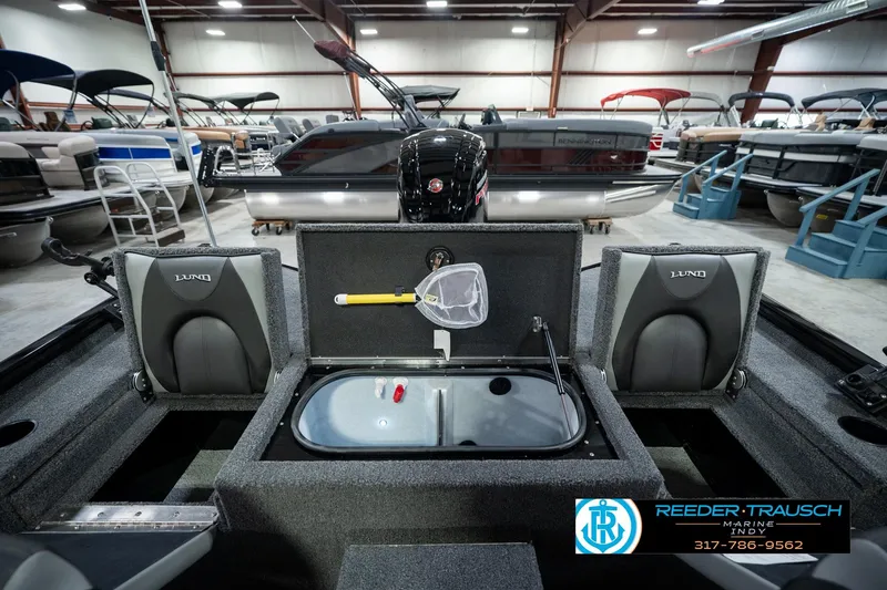 Slide: The Image of 2026 Lund 1875 Renegade boat interior with storage compartments and seating in a showroom. - 26