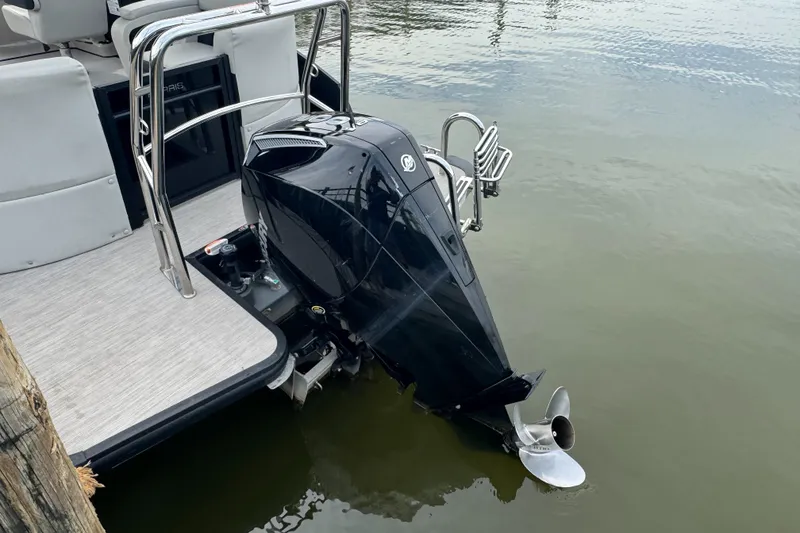 Slide: The Image of 2024 Harris Breeze 230 pontoon boat with sleek outboard motor in calm water. - 7
