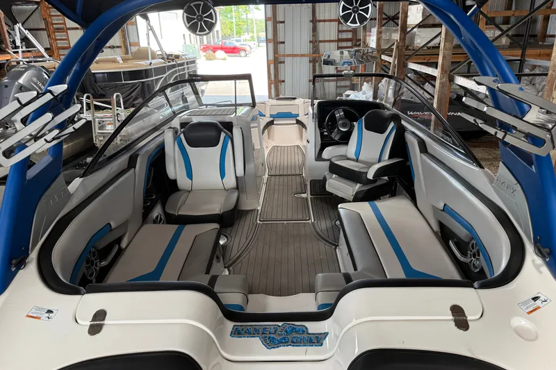 Slide: The Image of 2018 Yamaha Boats 242X E-Series interior with blue and white seating, in a storage facility. - 3