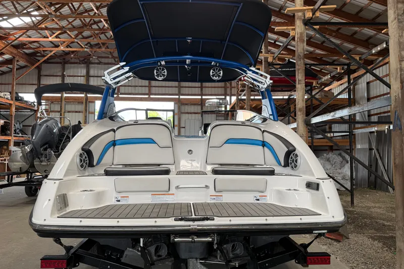 Slide: The Image of 2018 Yamaha Boats 242X E-Series in storage, showcasing rear seating and speakers. - 2