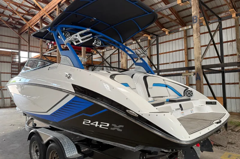 Slide: The Image of 2018 Yamaha Boats 242X E-Series in a warehouse, showcasing sleek design and vibrant blue accents. - 1