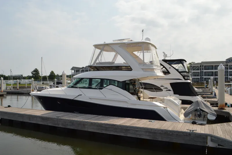 Slide: The Image of 2021 Tiara Yachts F44 Flybridge docked at a marina under a cloudy sky. - 5