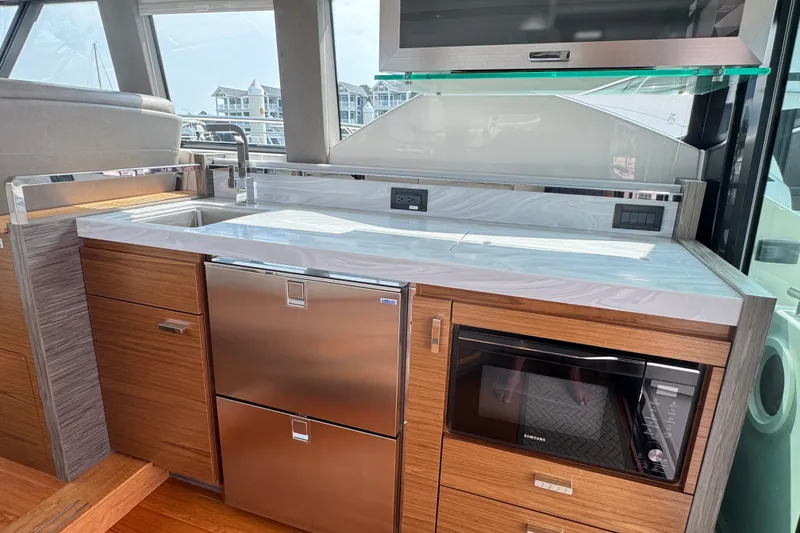 Slide: The Image of Modern kitchen area in 2021 Tiara Yachts F44 Flybridge with sleek appliances and wood cabinetry. - 23