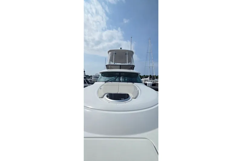 Slide: The Image of 2021 Tiara Yachts F44 Flybridge, sleek design under a partly cloudy sky. - 9