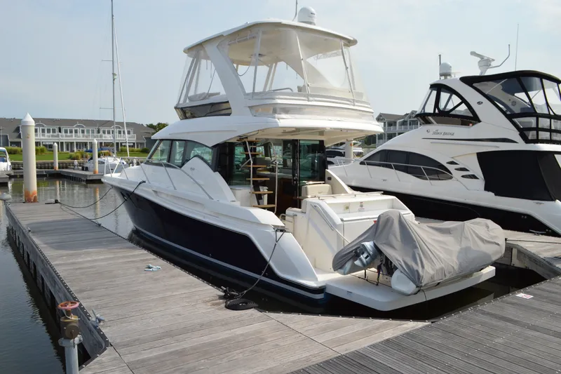 Slide: The Image of A 2021 Tiara Yachts F44 Flybridge docked. It features a sleek design and a covered flybridge. - 4