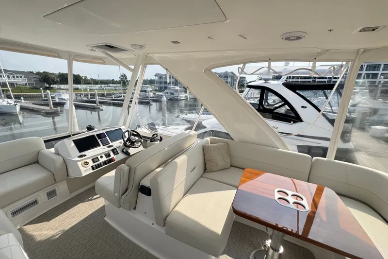 Slide: The Image of 2021 Tiara Yachts F44 Flybridge interior with helm, seating, and marina view. - 39