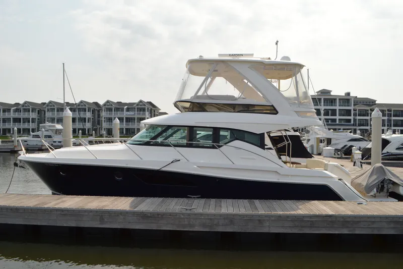 Slide: The Image of 2021 Tiara Yachts F44 Flybridge docked at marina, modern waterfront buildings in background. - 6