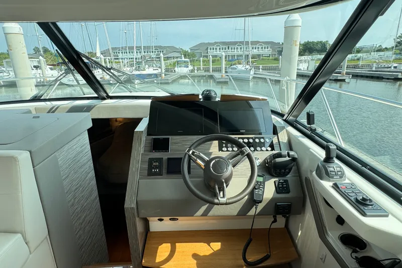 Slide: The Image of Helm of 2021 Tiara Yachts F44 Flybridge with modern controls and marina view. - 21