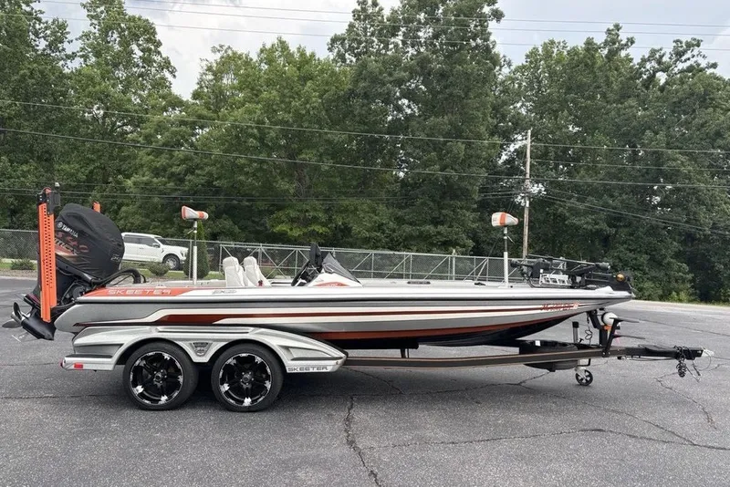 Slide: The Image of 2018 Skeeter FX21 bass boat on trailer, parked outdoors with trees in background. - 35