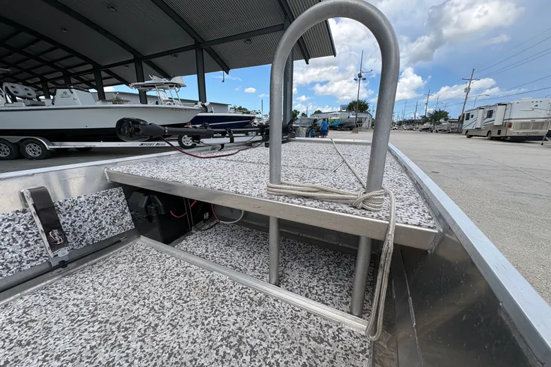 Slide: The Image of Aluminum boat interior with custom flooring, docked near other boats and RVs under a cloudy sky. - 11
