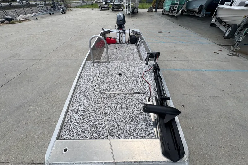 Slide: The Image of Custom 2023 model 14 boat with speckled deck, motor, and equipment, parked on concrete. - 10