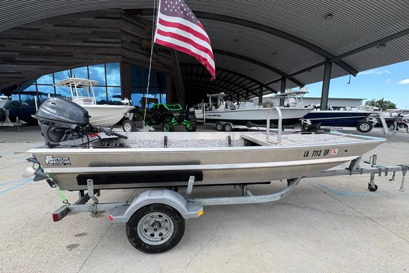 Slide: The Image of Aluminum fishing boat with Yamaha motor, American flag, and trailer in a marina setting. - 2