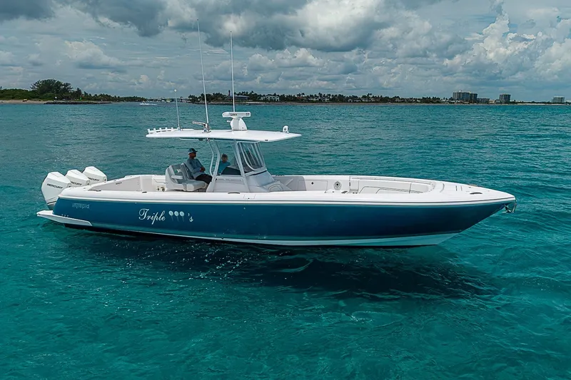 The Image of 2023 Intrepid 375 Nomad FE boat cruising on clear blue water under cloudy skies. - 0
