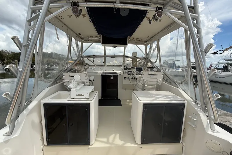 Slide: The Image of 2002 Carolina Classic 28 boat interior with helm, seating, and fishing equipment at a marina. - 11