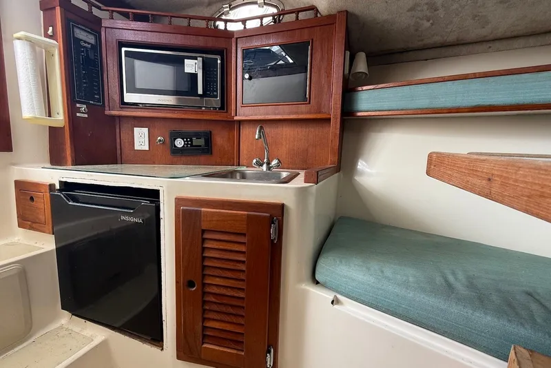Slide: The Image of 2002 Carolina Classic 28 boat interior with kitchenette, microwave, sink, and seating area. - 16