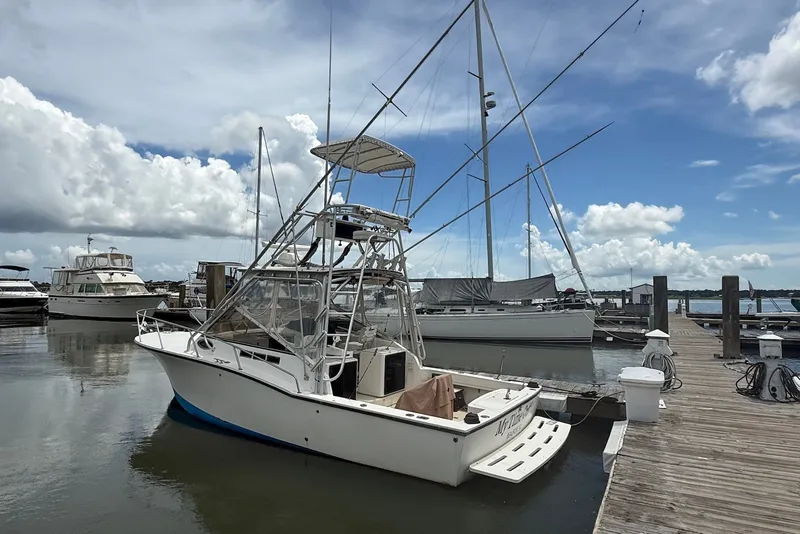 Slide: The Image of 2002 Carolina Classic 28 boat docked at marina under cloudy sky. - 1