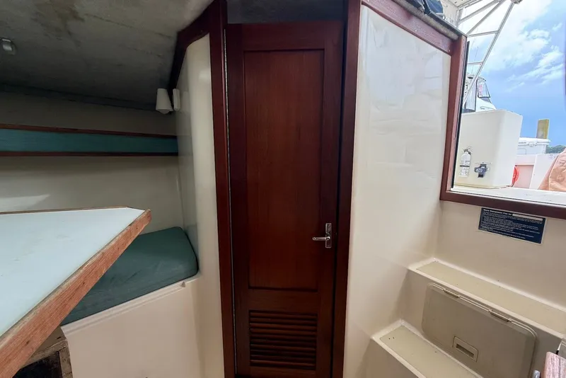 Slide: The Image of Interior cabin of a 2002 Carolina Classic 28 boat, featuring a wooden door and seating area. - 17