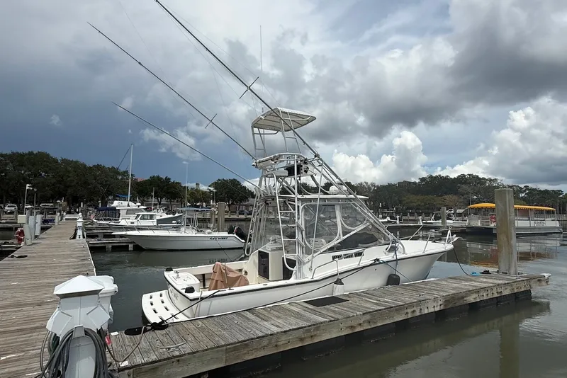 Slide: The Image of 2002 Carolina Classic 28 boat docked at a marina under cloudy skies. - 2