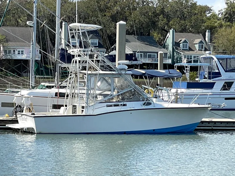 The Image of 2002 Carolina Classic 28 boat docked at a marina with houses in the background. - 0