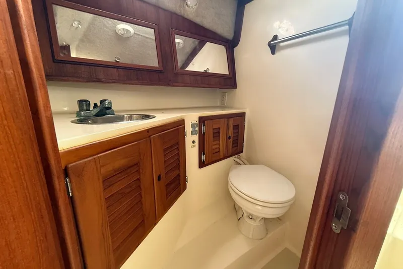 Slide: The Image of 2002 Carolina Classic 28 boat bathroom with wooden cabinets and compact design. - 18