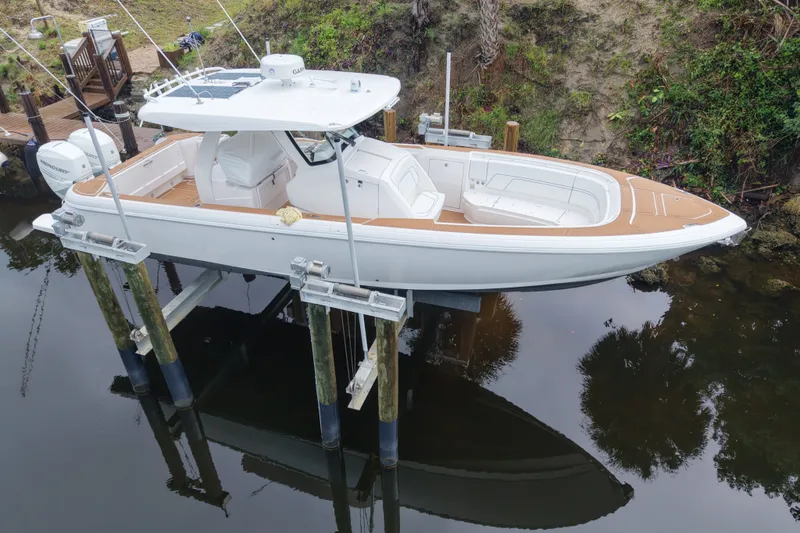 Slide: The Image of 2022 Intrepid 345 Nomad SE boat on lift, featuring sleek design and spacious deck. - 2