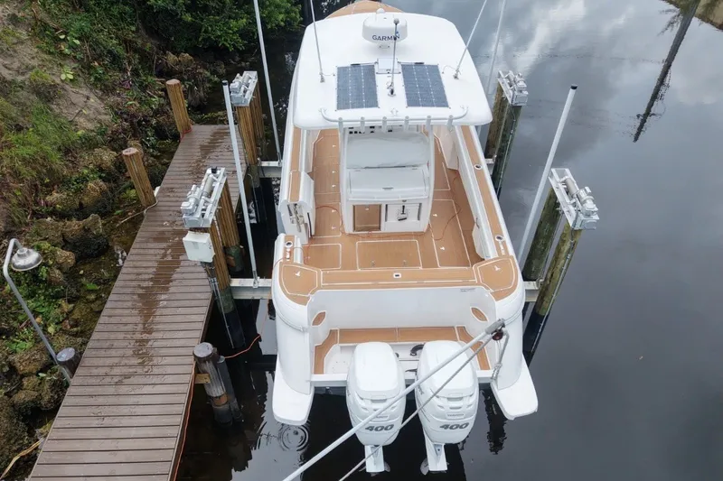 Slide: The Image of A 2022 Intrepid 345 Nomad SE at a dock. It features twin outboard engines and a spacious deck. - 4