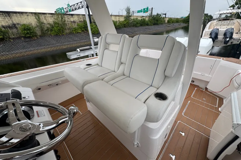 Slide: The Image of 2022 Intrepid 345 Nomad SE boat interior with plush seating and sleek steering wheel. - 16