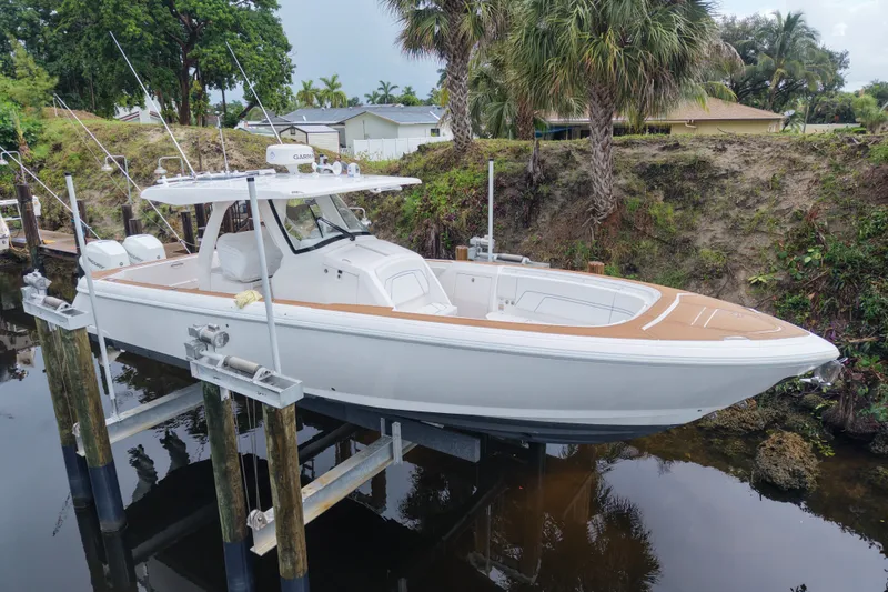 The Image of 2022 Intrepid 345 Nomad SE boat on lift, surrounded by lush greenery. - 0