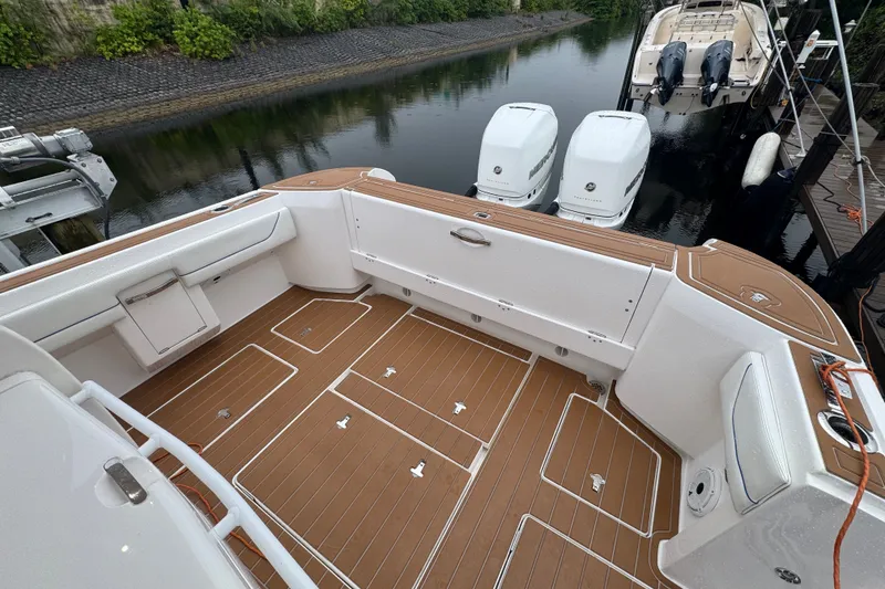 Slide: The Image of 2022 Intrepid 345 Nomad SE boat deck with twin engines, docked by calm water. - 19