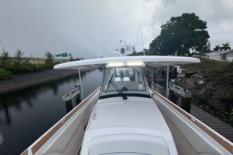 Slide: The Image of 2022 Intrepid 345 Nomad SE boat docked on a calm waterway under cloudy skies. - 15