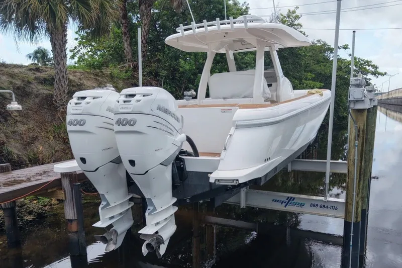 Slide: The Image of A 2022 Intrepid 345 Nomad SE on a boat lift, featuring twin outboard engines. - 6