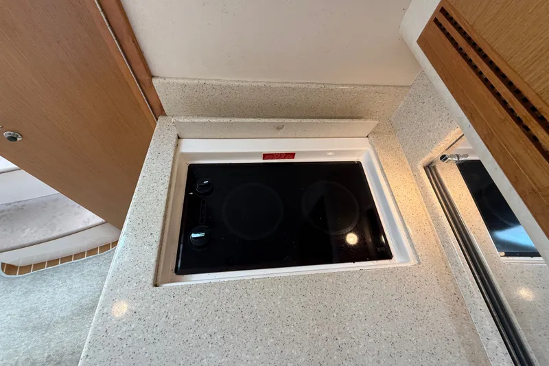 Slide: The Image of 2007 Cabo 32 Express yacht kitchen with sleek black cooktop and beige countertop. - 65